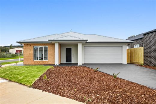 The front of 11 Xavier Road: a single-storey brick and render home with a double garage and a mulched front garden.
