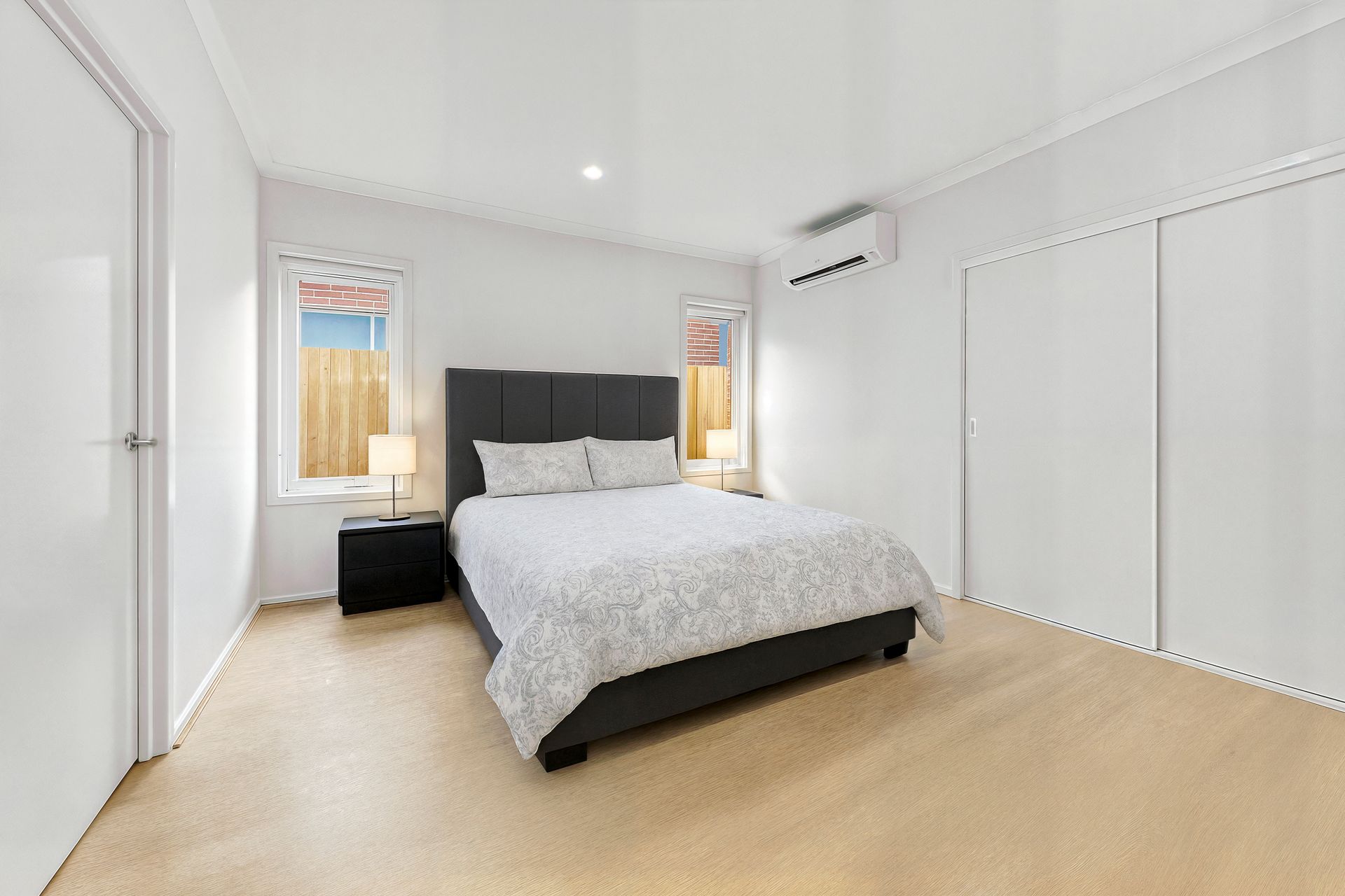 A bedroom with a double bed, built-in robe and split-system air conditioner.