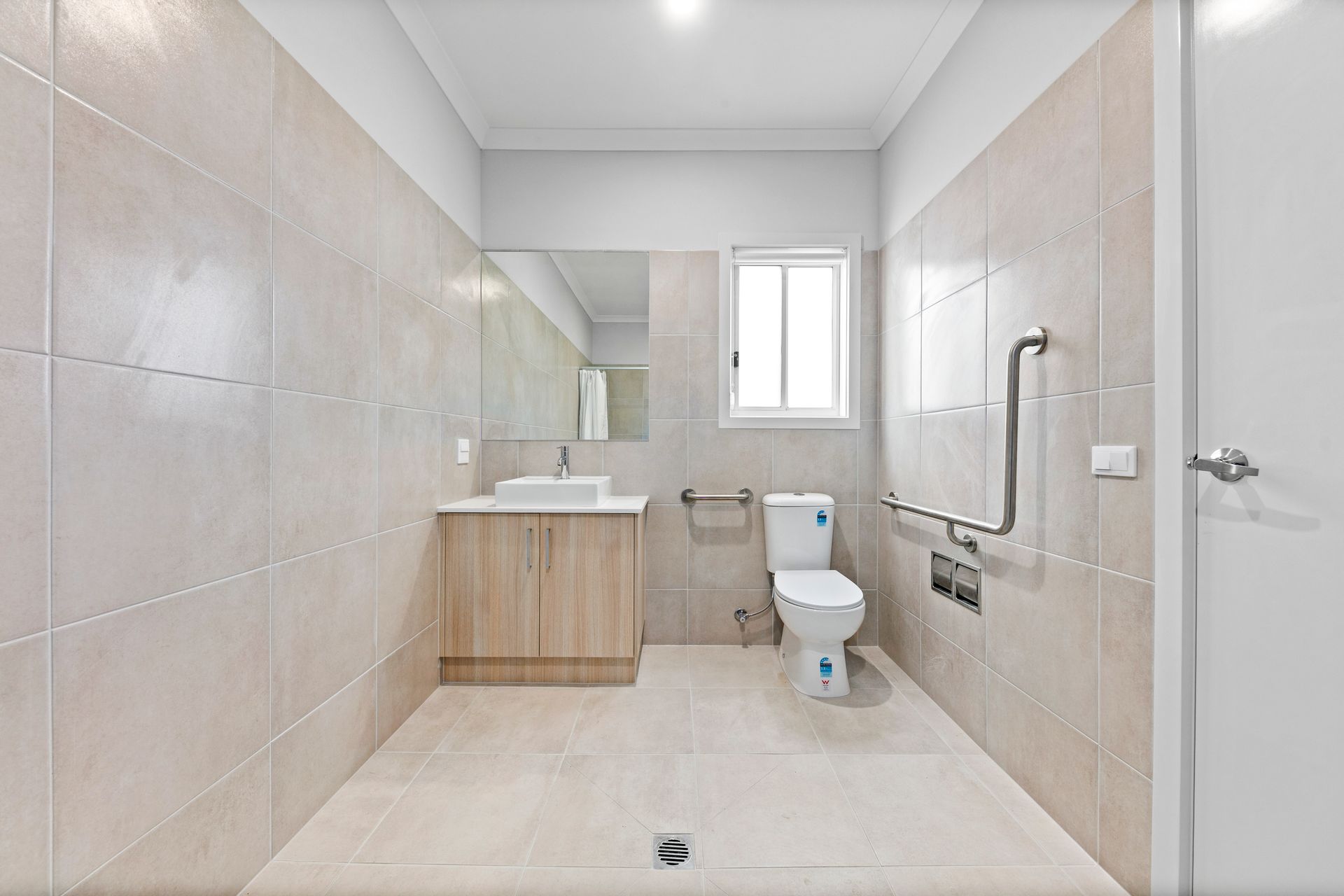 An accessible ensuite with grab rails, a vanity and a step-free floor.