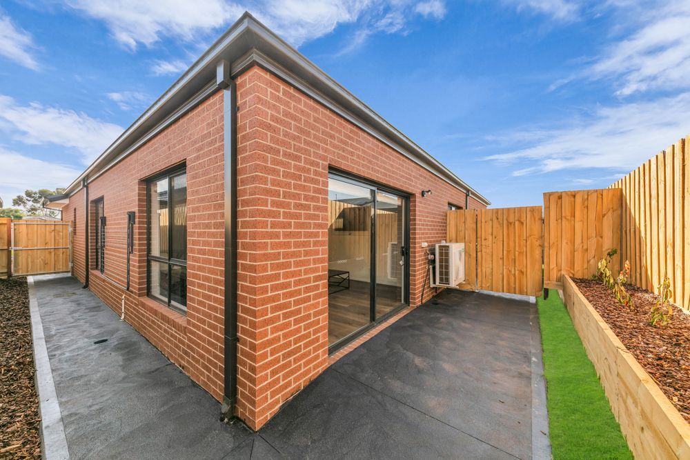 The rear of the home, with a sliding door, paved area and fenced yard.