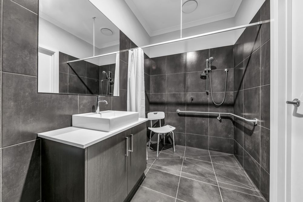 An accessible bathroom with a step-free shower, grab rails and a shower chair.